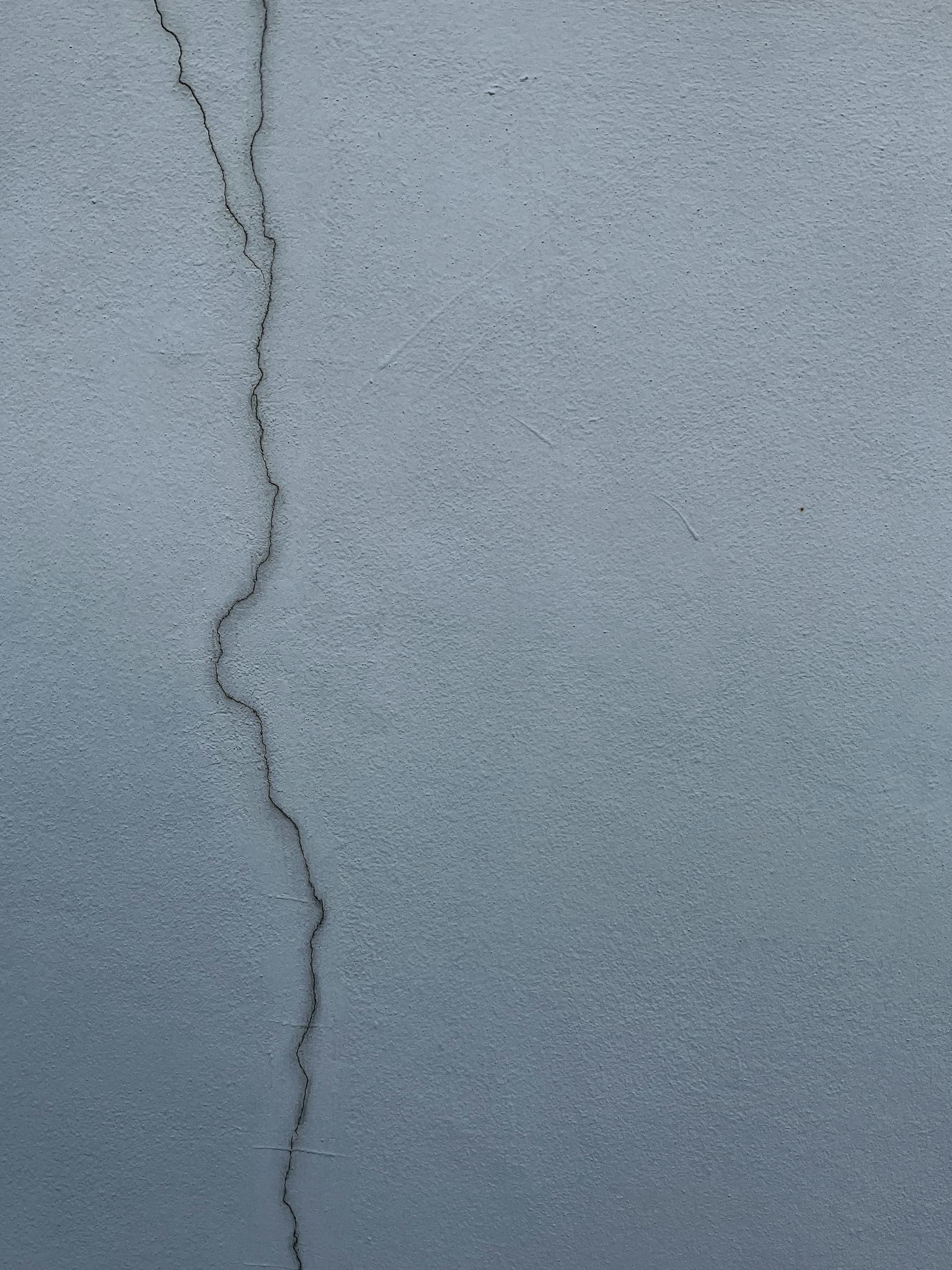 Close-up of a cracked cement wall displaying texture and structural detail.