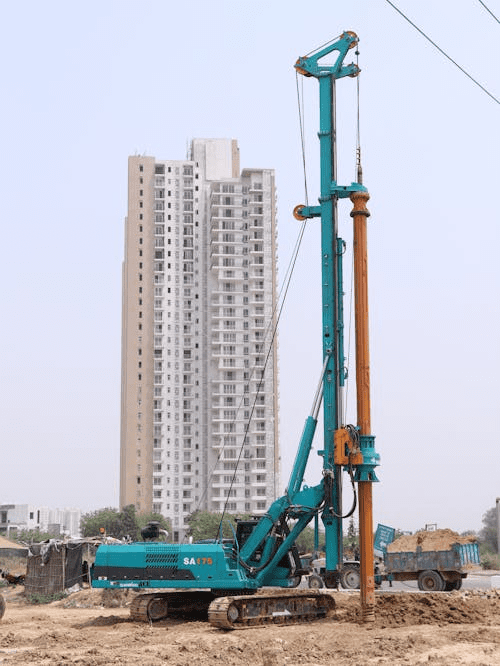 Piling rig installing a deep foundation pile at a construction site near tall buildings